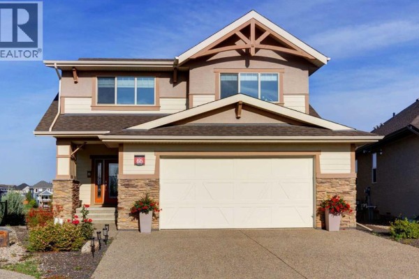 Front exterior of a two-story house with a beige stucco finish and stone accents. - 66 Legacy Green Se, Calgary