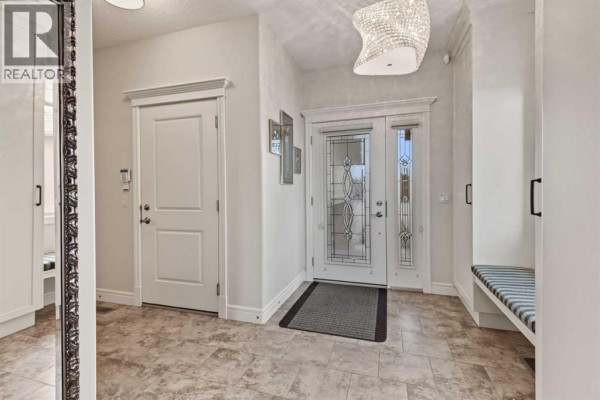 Interior entryway with tiled flooring, double doors, and a bench seat. - 66 Legacy Green Se, Calgary