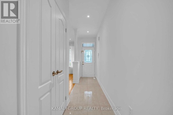 Tiled entryway hallway with white walls, two closet doors, and a glass-paned front door. - 66 Longwood Avenue, Richmond Hill