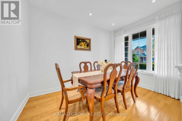 Dining room with a large window overlooking houses, light wood floors, and a painting on the wall. - 66 Longwood Avenue, Richmond Hill