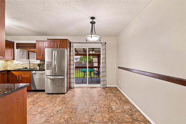 Kitchen area with stainless steel refrigerator and patio door leading to a covered deck. - 66 Meighen Bay, Winnipeg