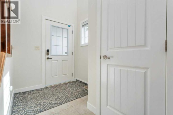 Interior entryway with a tiled floor, white door, and a patterned rug. - 66 Morris Court, Blackfalds