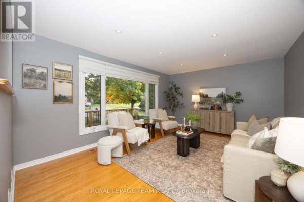 Living room with grey walls, hardwood floors, a large window, and light-colored furniture. - 66 Still Water Drive, Ottawa