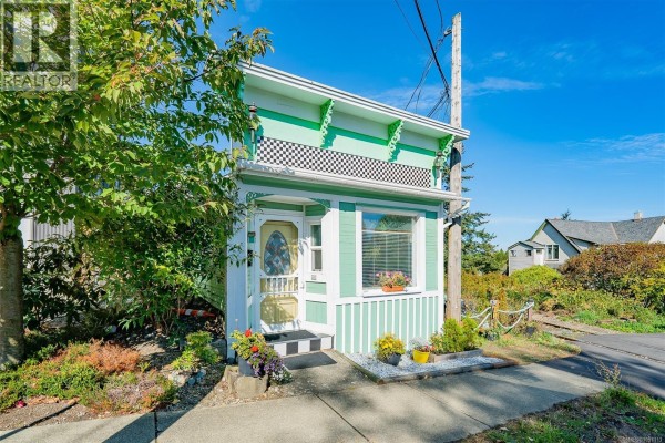 Front view of a quaint green house with decorative trim and a small porch. - 660 Albert St, Nanaimo