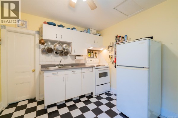 Kitchen with white cabinets, white appliances, and a black and white checkered floor. - 660 Albert St, Nanaimo