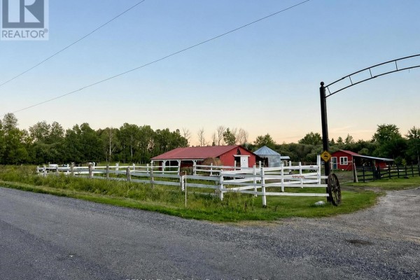Dusk view of the rural property with white fences, red outbuildings, and a large metal archway. - 661 Stewart Road, Alberton
