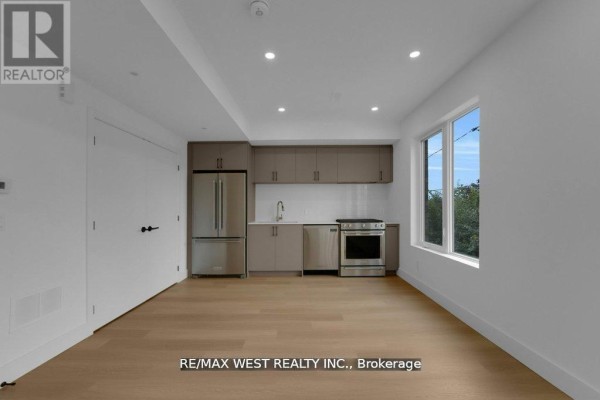 Bright living area featuring light wood flooring and modern kitchen layout with natural light - 661 Winona Drive, Toronto