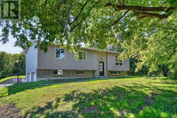 Side view of a grey split-level house with a stone accent around the entrance and windows. - 6614 Parkway Road, Ottawa