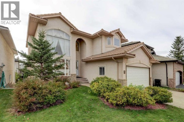 Front exterior of a stucco house with a stepped walkway and large windows. - 662 Arbour Lake Drive Nw, Calgary