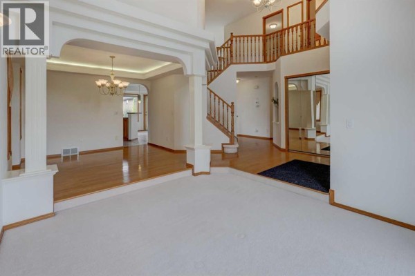 Interior view showing a living room, dining room, and a staircase with wood railings. - 662 Arbour Lake Drive Nw, Calgary