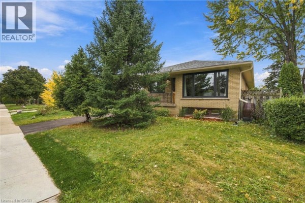 Side view of a yellow brick house with a long driveway and mature trees. - 662 Dynes Road, Burlington