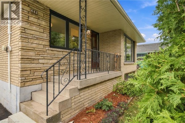 Close-up of the concrete front steps with a black metal railing and yellow brick siding. - 662 Dynes Road, Burlington