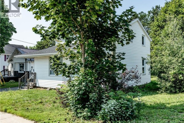 Side view of the white vinyl-sided house with mature trees and greenery. - 662 Evangeline, Dieppe