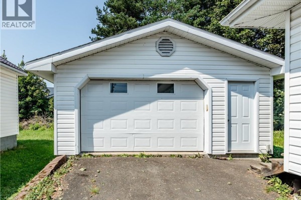 White vinyl-sided detached garage with a double door and a side entrance door. - 662 Evangeline, Dieppe