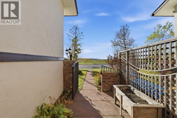 View of a pathway leading towards the street, bordered by brick pillars and a metal gate. - 6624 37 Street Sw, Calgary