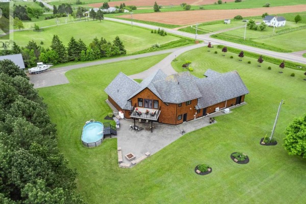 Wide shot of the house with a circular driveway and adjacent wooded area. - 6624 Route 13, Mayfield