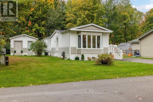 Side view of a white and tan manufactured home with a detached shed and lawn. - 6636 Vista Patrick Private, Ottawa