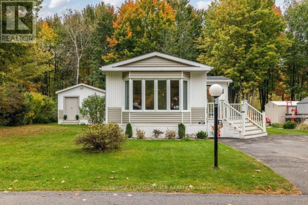 Front of a manufactured home showing a bay window, porch, and detached shed. - 6636 Vista Patrick Private, Ottawa