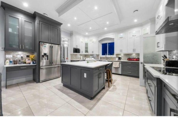 Spacious modern kitchen with dark grey island, white cabinets, stainless steel appliances, and tiled floor. - 6637 121a Street, Surrey