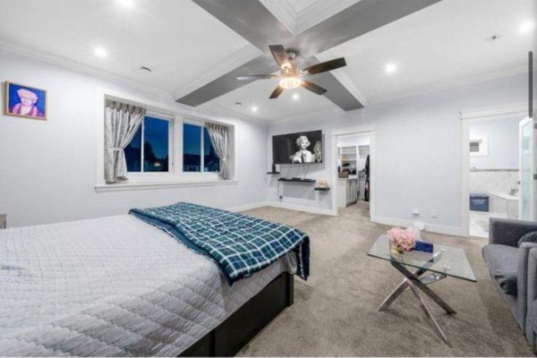 Large bedroom with king-size bed, grey carpet, ceiling fan, television, and adjoining bathroom. - 6637 121a Street, Surrey