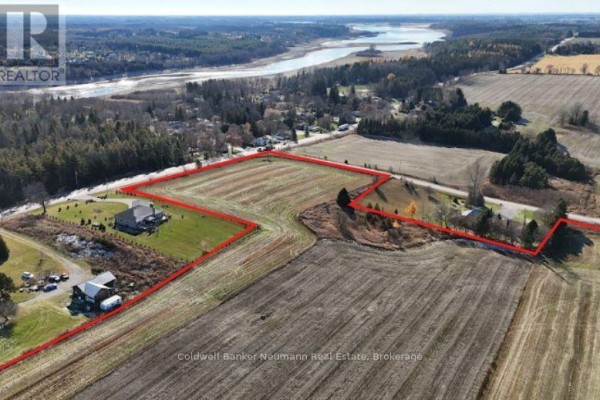 Aerial view of farmland with houses, barns, and a body of water in the distance. - 6641 Seventh Line, Centre Wellington