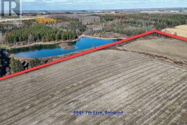 Aerial view of a farm showing fields, a pond, and surrounding trees under a blue sky. - 6641 Seventh Line, Centre Wellington