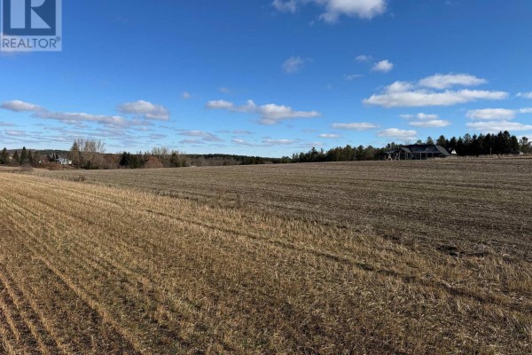 Wide view of a harvested farm field with houses and trees in the background. - 6641 Seventh Line, Centre Wellington