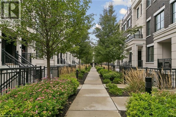 Pathways with landscaping and trees between multi-story townhouses. - 665 Cricklewood Drive Unit# 703, Mississauga