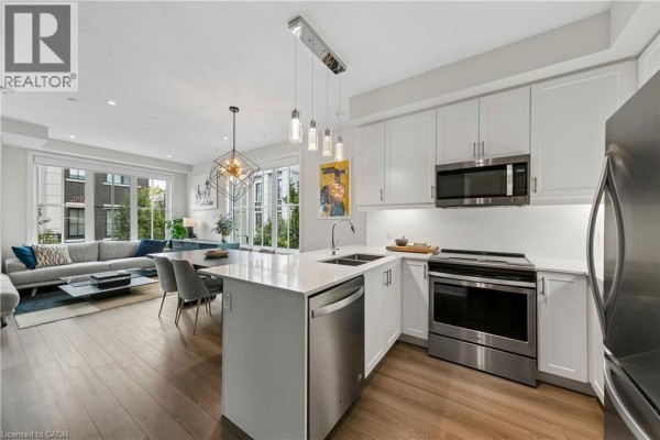 Open concept kitchen and living room with island and stainless steel appliances. - 665 Cricklewood Drive Unit# 703, Mississauga