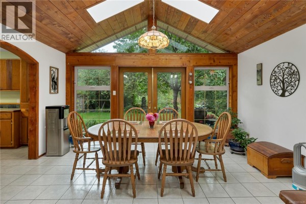 Sunroom with a wooden vaulted ceiling, skylights, and glass doors opening to a garden view. - 665 Fox Rd, Quadra Island