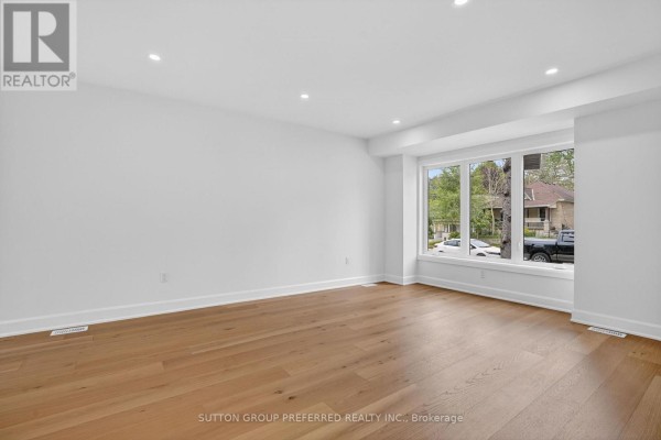 Bedroom with a queen-size bed, dresser, mounted television, and a window with a neighborhood view. - 665 Piccadilly Street, London East