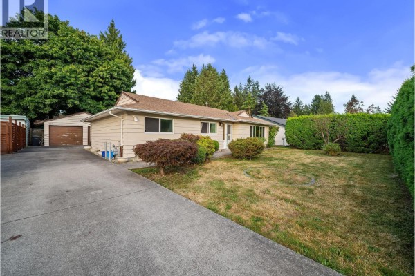 Wide shot of the beige house, asphalt driveway, detached garage, and mature trees. - 667 Cypress Street, Coquitlam