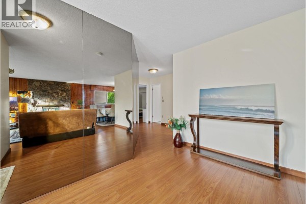 Living room with a stone fireplace, wood-paneled walls, large picture windows, and plush furnishings. - 667 Cypress Street, Coquitlam