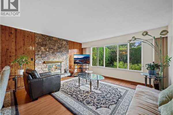 Open-concept living and dining area with wood floors, stone fireplace, dining table, and chairs. - 667 Cypress Street, Coquitlam