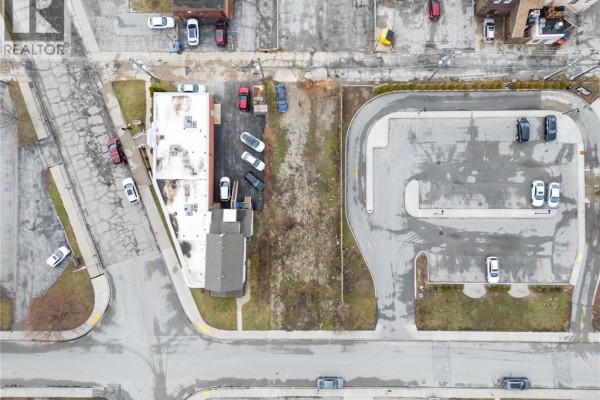 Overview of the lot with nearby commercial buildings and parking areas visible. - 667 Windsor Avenue, Windsor