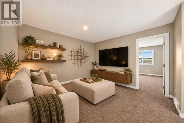 Family room with sofa, ottoman, television, and wall decor, with view into another room. - 668 Savanna Drive Ne, Calgary