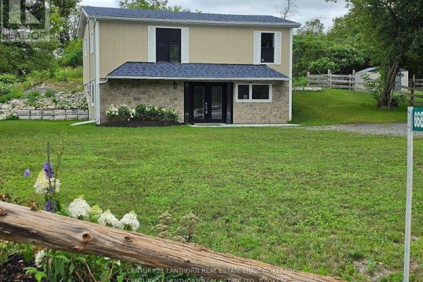 Exterior of a beige and stone two-story house with double glass doors. - 6682 Wheeler Street S, Stone Mills