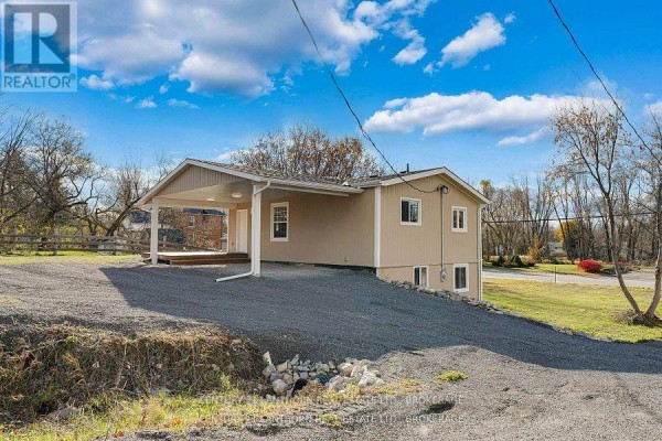 Angle showing the house with covered carport and surrounding landscape. - 6682 Wheeler Street, Stone Mills