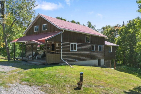Bright kitchen with wooden cabinetry, dining table, and large windows overlooking the yard. - 6683 Old Hastings Road, Tudor And Cashel