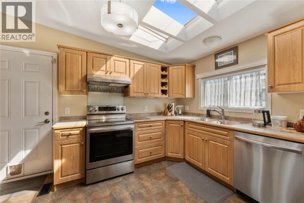Kitchen with light wood cabinets, stainless steel appliances, and a sink with skylights. - 6688 Tronson Road Unit# 31, Vernon