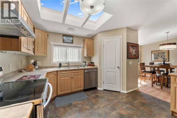 View of kitchen and dining area with light wood cabinets and skylights. - 6688 Tronson Road Unit# 31, Vernon