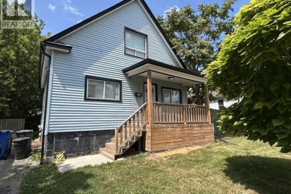 Side view of the light blue house showing the wooden porch, steps, and windows. - 669 Bridge Avenue, Windsor
