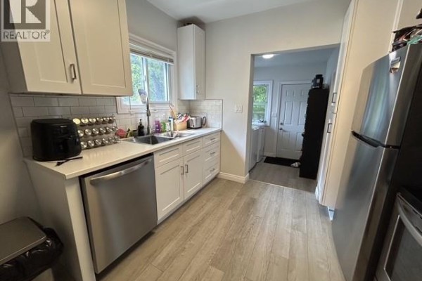 Modern kitchen with white cabinets, stainless steel appliances, and light wood-look flooring. - 669 Bridge Avenue, Windsor