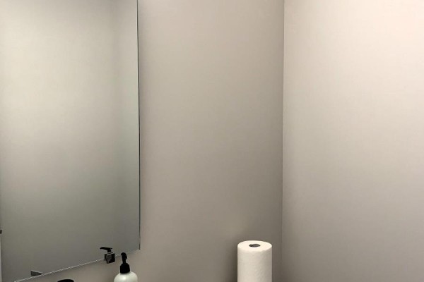 A modern powder room with a large mirror, gray walls, and a roll of paper towels. - 669 Honeydew Street, Ottawa