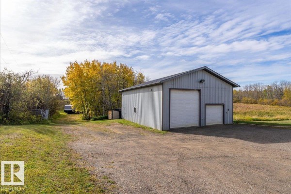 Interior of a workshop with a car lift, tool chests, storage cabinets, and weightlifting equipment. - 67 50514 Range Road 202, Rural Beaver County