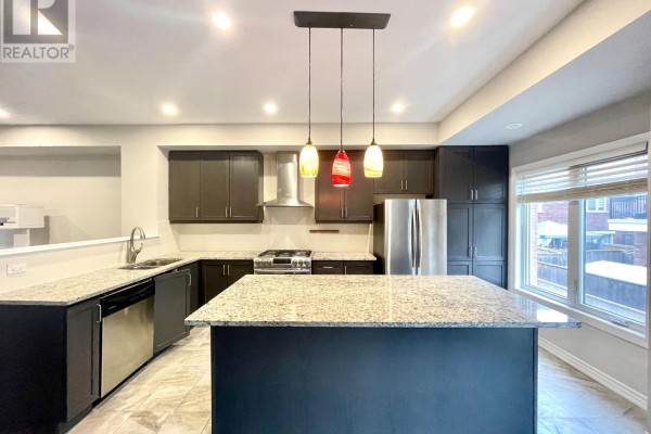 Modern kitchen with dark cabinets, granite countertops, stainless steel appliances, and a large island. - 67 Antibes Drive, Toronto