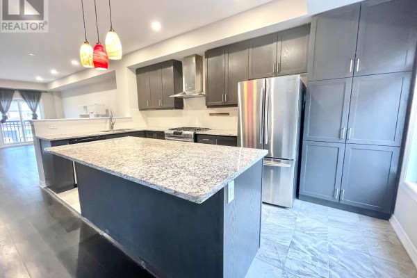 Kitchen with dark grey cabinets, granite island, stainless steel refrigerator and range, overlooking dining area. - 67 Antibes Drive, Toronto