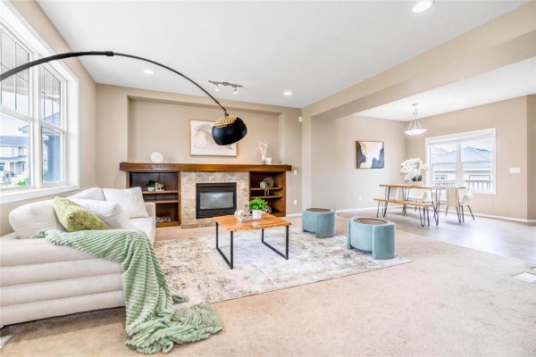 Small room with beige carpet, beige walls, a wooden desk, a fabric office chair, and a large window. - 67 Bellflower Road, Winnipeg