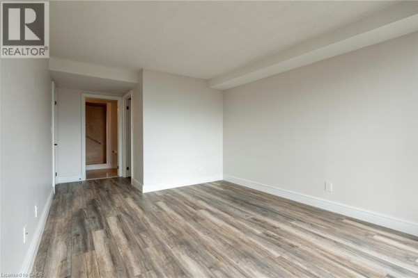 Empty room with wood-look flooring and open doorway - 67 Caroline Street S Unit# 13a Hamilton