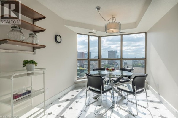 Glass dining table with black chairs, pendant light, city view through large windows, and geometric tile floor - 67 Caroline Street S Unit# 13a Hamilton